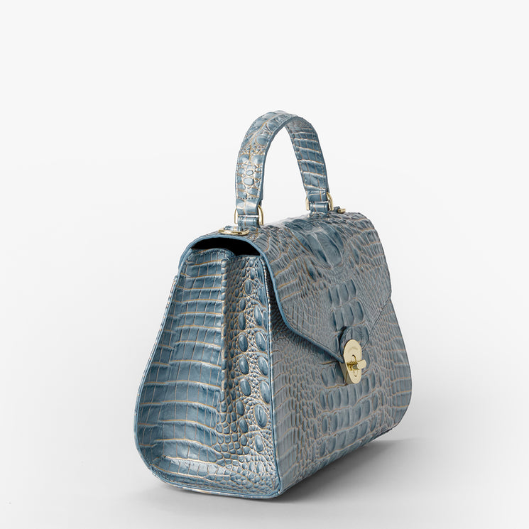 A structured blue crocodile-embossed handbag with a top handle and gold-tone hardware, photographed on a clean white background.
