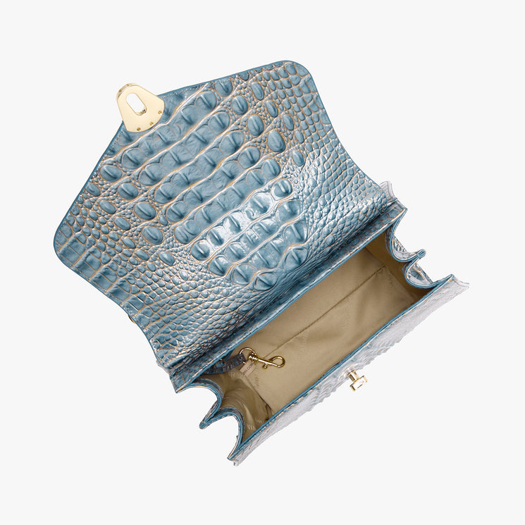A light blue crocodile-embossed leather bag shown open, revealing a beige interior lining and gold-tone hardware, set against a plain white background.