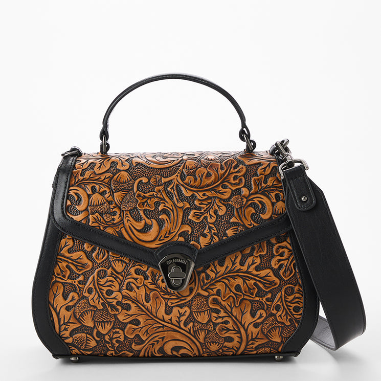 Brown leather handbag with intricate patterns on a white background. Annalise front view with strap.