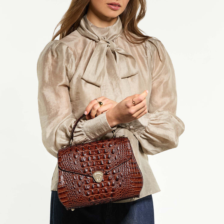 Woman holding Annalise handbag on arm against a white background