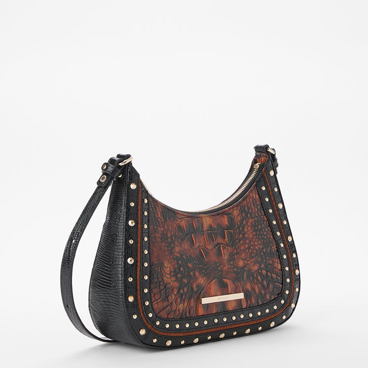 A crescent-shaped shoulder bag with a black crocodile-embossed leather body, a brown alligator-patterned front, and silver-tone studs along the edges, shown on a white background.