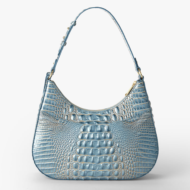 A light blue crocodile-embossed leather shoulder bag with a curved hobo silhouette and gold-tone hardware, shown on a clean white background.