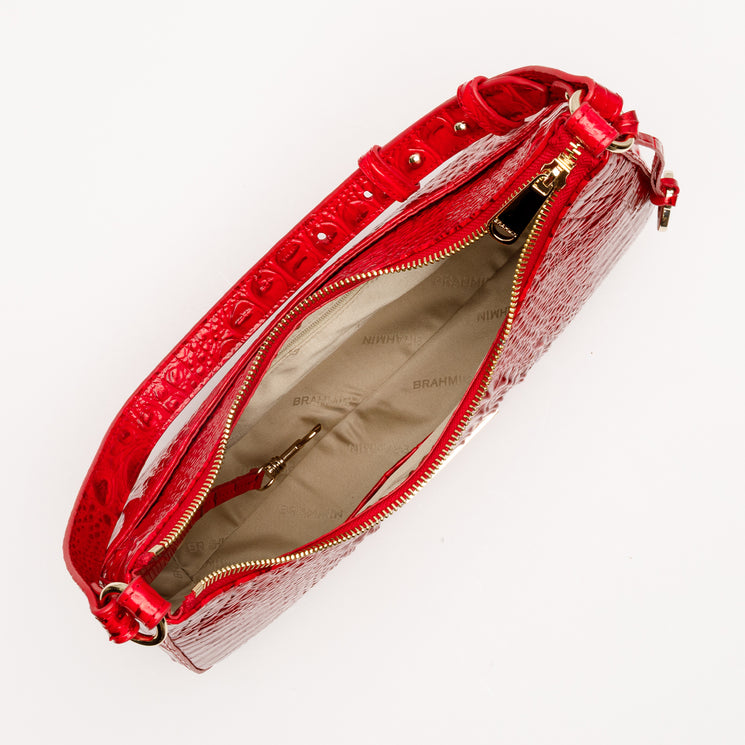 Brahmin Stephie crescent-shaped shoulder bag in holiday red featuring a textured, embossed pattern, gold-tone zipper closure, and a beige fabric-lined interior with an attached key clip.