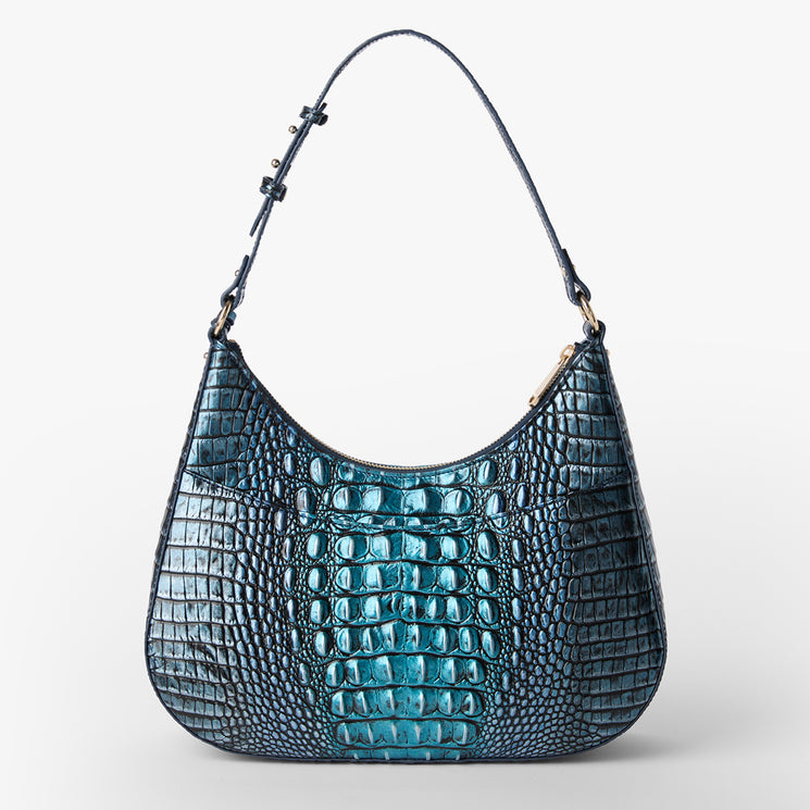 BRAHMIN Stephie blue shoulder bag featuring embossed textured pattern, crescent silhouette, adjustable strap with gold-tone hardware, and visible brand detail; displayed on a plain white background.