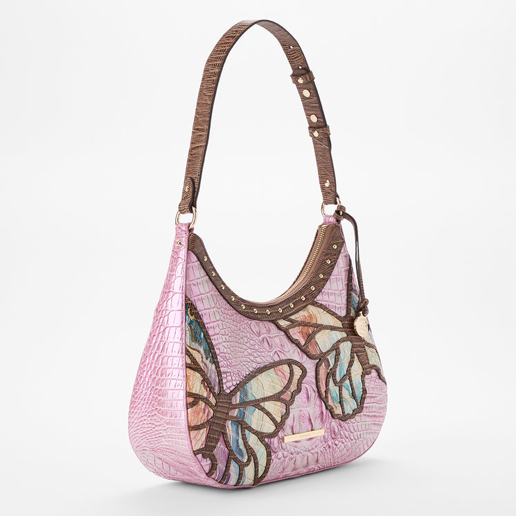 Brahmin pink textured handbag with brown shoulder strap, colorful butterfly prints, gold-tone hardware, structured silhouette; shown on white background. No interior features visible.