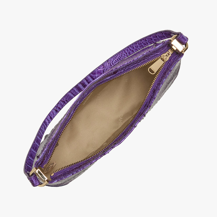 Top view of an open Brahmin purple textured handbag with gold zipper, short top handle with gold hardware, beige fabric lining, and single interior compartment. Classic structured silhouette perfect for hand carry.