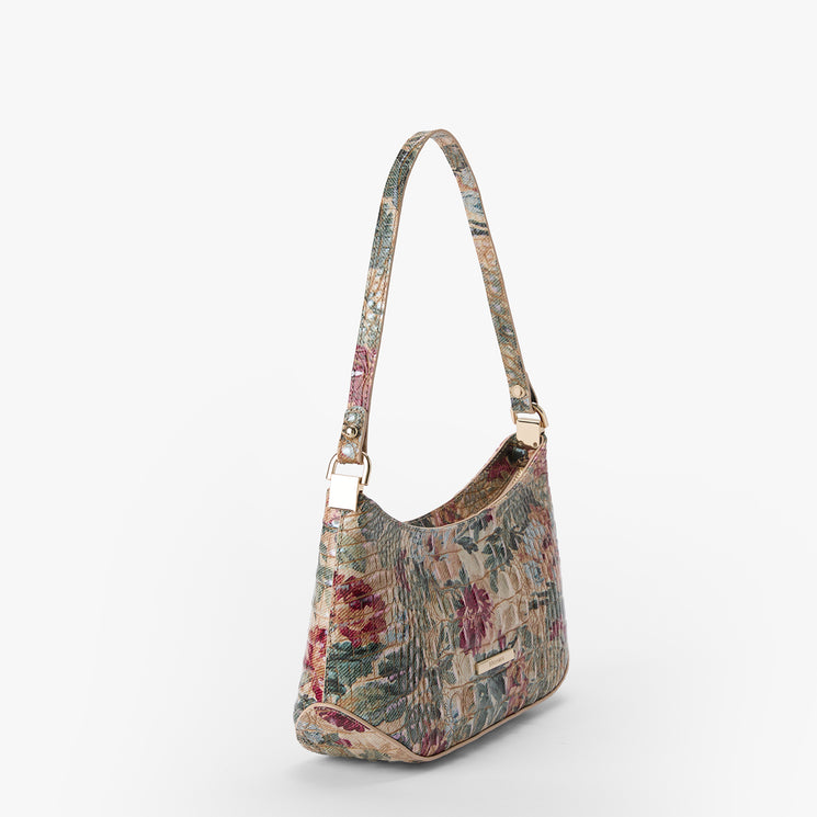 A shoulder bag with a vintage floral tapestry pattern in muted red, green, and beige tones, featuring gold-tone hardware and a matching patterned strap, shown against a plain light gray background.