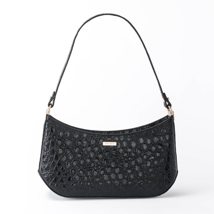 BRAHMIN Lilibeth curved shoulder bag in black with a crocodile-embossed texture, gold hardware, and a short strap, displayed against a white background. Elegant silhouette and luxury finish are visible.