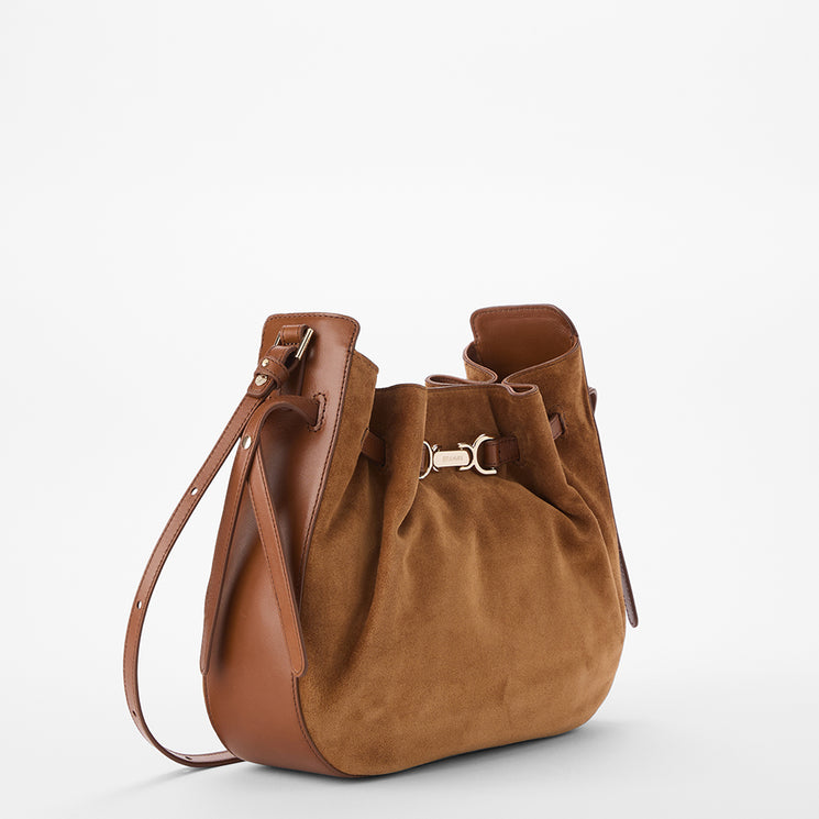 A brown suede and leather shoulder bag with a drawstring closure and gold-tone hardware, photographed on a clean white background.