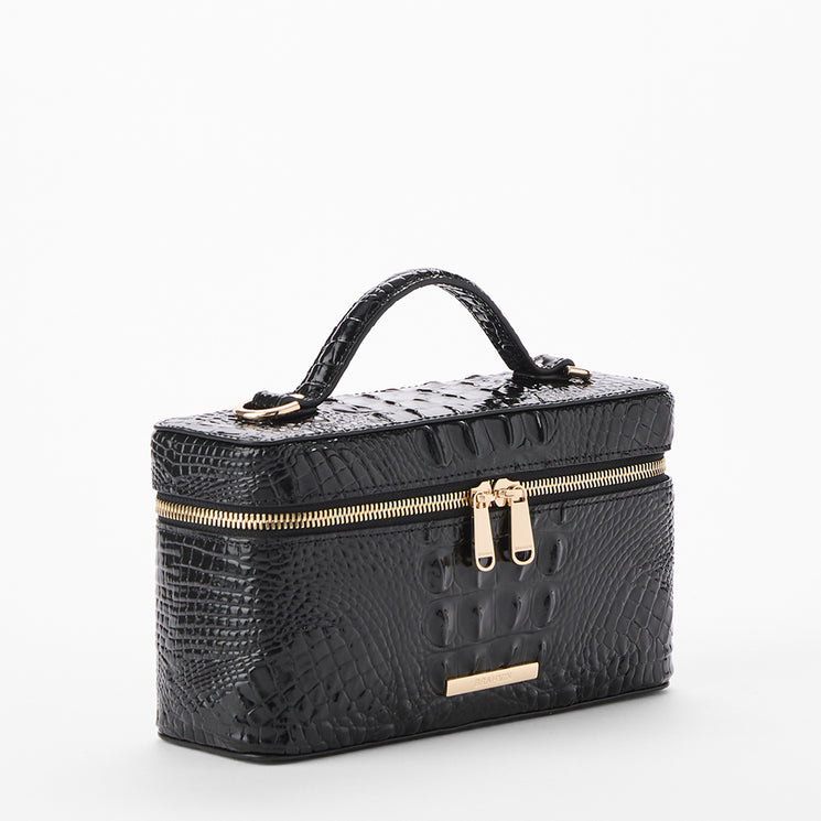 Black crocodile-embossed leather cosmetic case with a top handle, gold-tone zippers, and a small gold plaque on the front, shown on a light gray background. Side view.