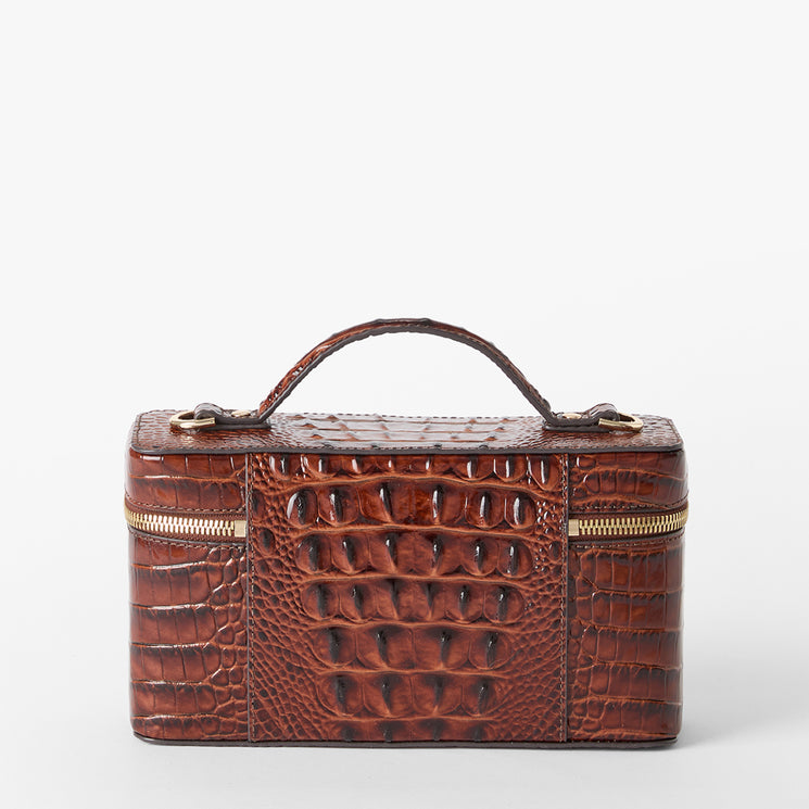 A brown crocodile-embossed leather cosmetic case with a top handle, gold-tone zippers, and a structured rectangular shape, shown against a plain light gray background. Back view.