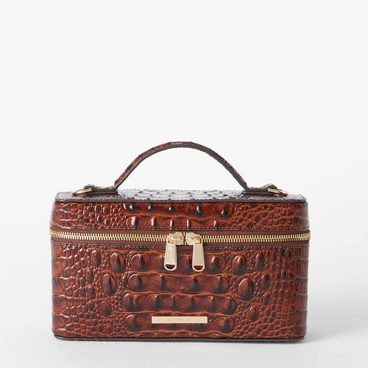 A brown crocodile-embossed leather cosmetic case with a top handle, double zipper closure, and gold-tone hardware, photographed on a clean white background. Front view without strap.