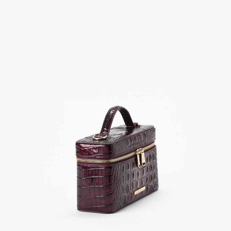 A small structured handbag with a crocodile-embossed texture in deep burgundy, featuring a top handle, gold-tone zippers, and a small gold Brahmin plaque on a clean white background.
