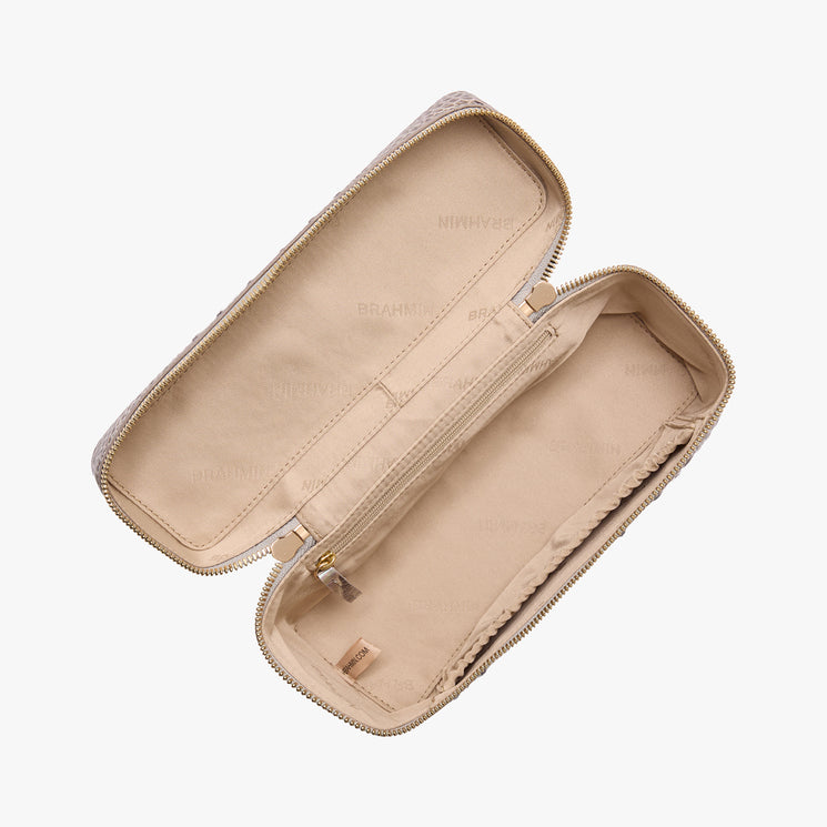 Brahmin beige rectangular zippered pouch with visible fabric lining, open to reveal a center zip pocket, side compartment, gold-tone hardware, and BRAHMIN branding on the interior.