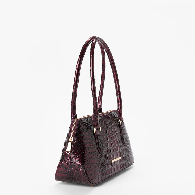 A dark burgundy crocodile-embossed handbag with double top handles and gold-tone hardware, shown from a three-quarter angle on a light gray background.
