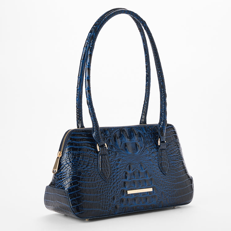 A dark blue crocodile-embossed handbag with gold-tone hardware, dual top handles, and a zip-top closure, photographed on a clean white background. Side view.