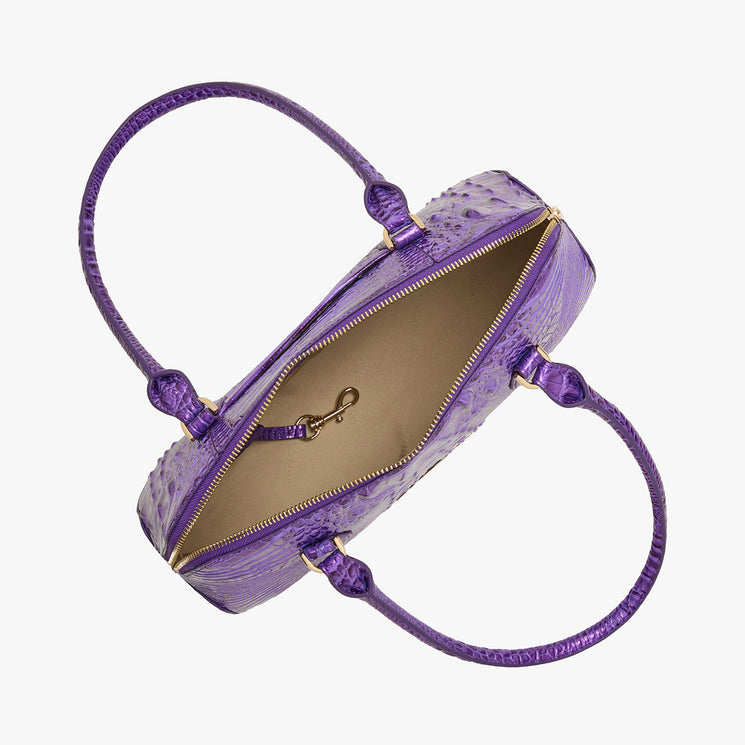 Top view of a Brahmin purple textured handbag with two top handles, open zipper, beige interior lining, and gold clasp inside. Features structured silhouette and visible hardware against a white background.