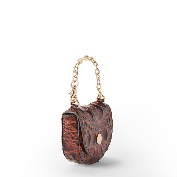The side of a small brown crocodile-embossed leather handbag with a gold-tone chain handle and a round gold-tone front clasp, photographed on a clean white background.