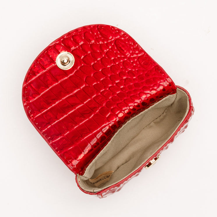 Brahmin Joy Pouch in Tinsel Red with a glossy, embossed texture, fold-over flap, and gold-tone snap closure, shown open to reveal a fabric-lined interior.