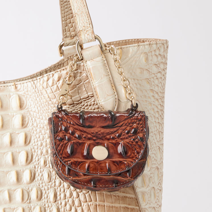 A close-up of a contour crocodile-embossed tote with a small brown crocodile-embossed pouch hanging from a gold chain strap, set against a plain light gray background.