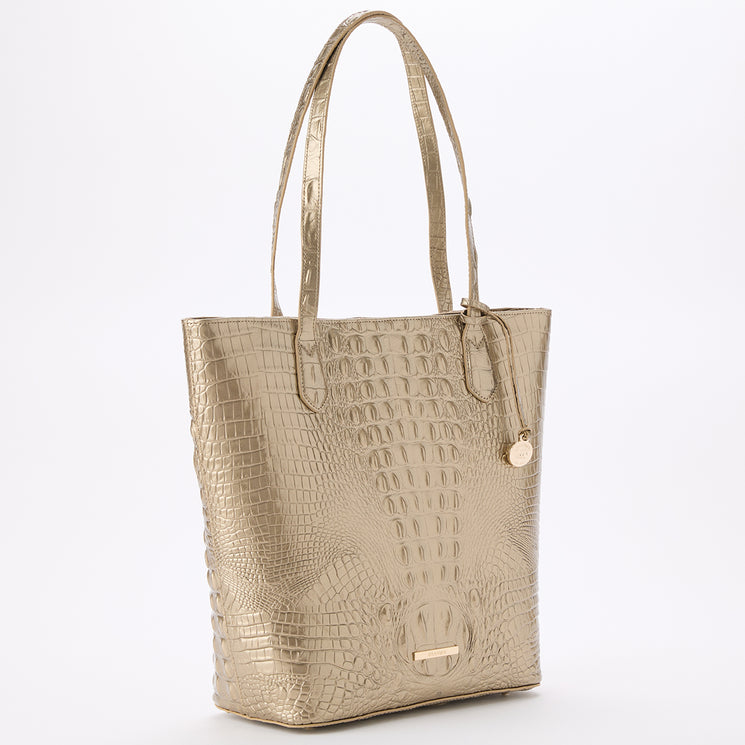BRAHMIN Laurel tote in gold textured leather with an embossed pattern, dual shoulder straps, round Brahmin logo tag, structured silhouette. Bag stands upright on a plain white background, no interior visible.