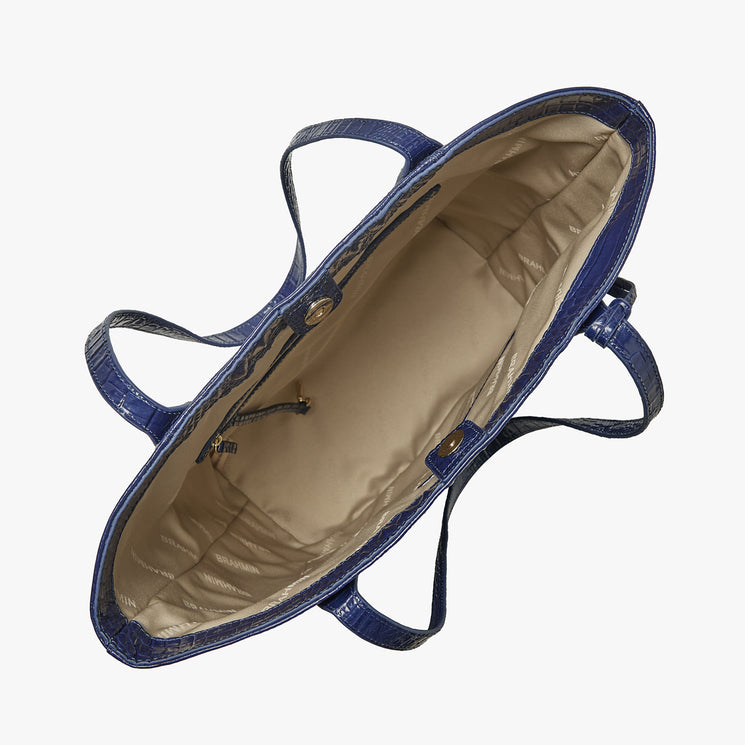 Top view of the Brahmin Laurel tote in midnight blue leather with beige lining, dual top handles, gold-tone snap closures, exterior zip pocket, and a spacious interior; classic silhouette for shoulder or hand carry.