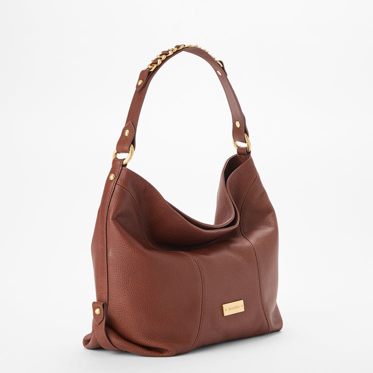 Brahmin brown handbag with gold hardware, wide shoulder strap with chain accents, and front gold nameplate, shown on a plain white background. Structured silhouette; details of interior not visible in this view.