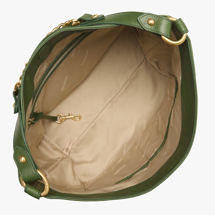 Top view of an open Brahmin green handbag with beige lining, gold-tone hardware, inner zip pocket, clasp hook, subtle text pattern on the interior, and spacious construction.