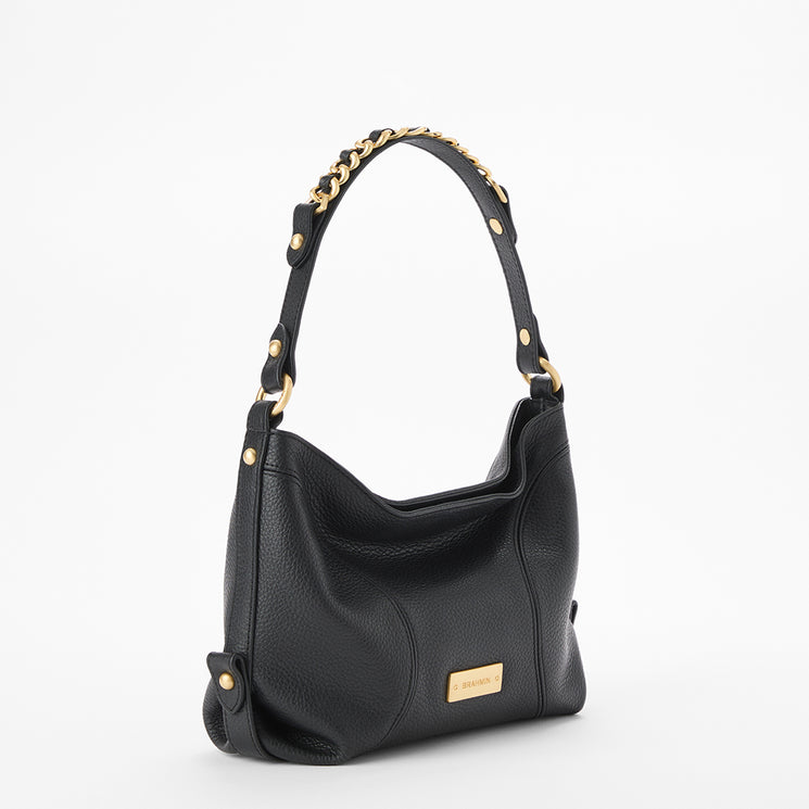 Brahmin black handbag with gold hardware, short chain-detailed handle, and signature gold logo plaque on the front. Structured silhouette shown on a plain white background.