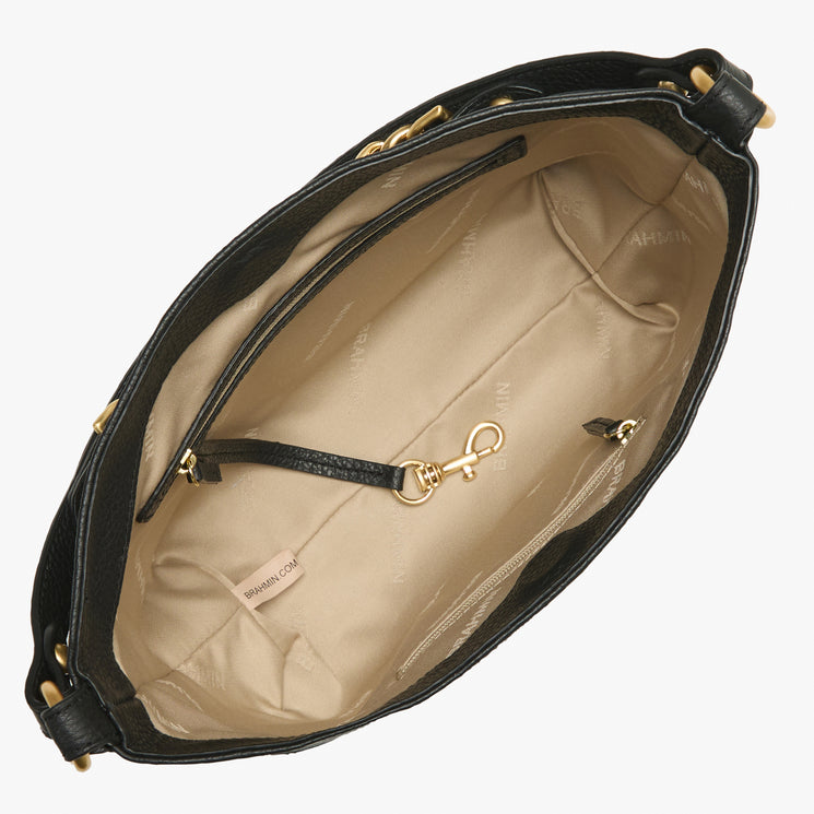 Top view of an open Brahmin black handbag with beige lining, gold hardware, interior zip pocket, gold clip closure, small sewn label with Brahmin branding, and visible textured details on the exterior.