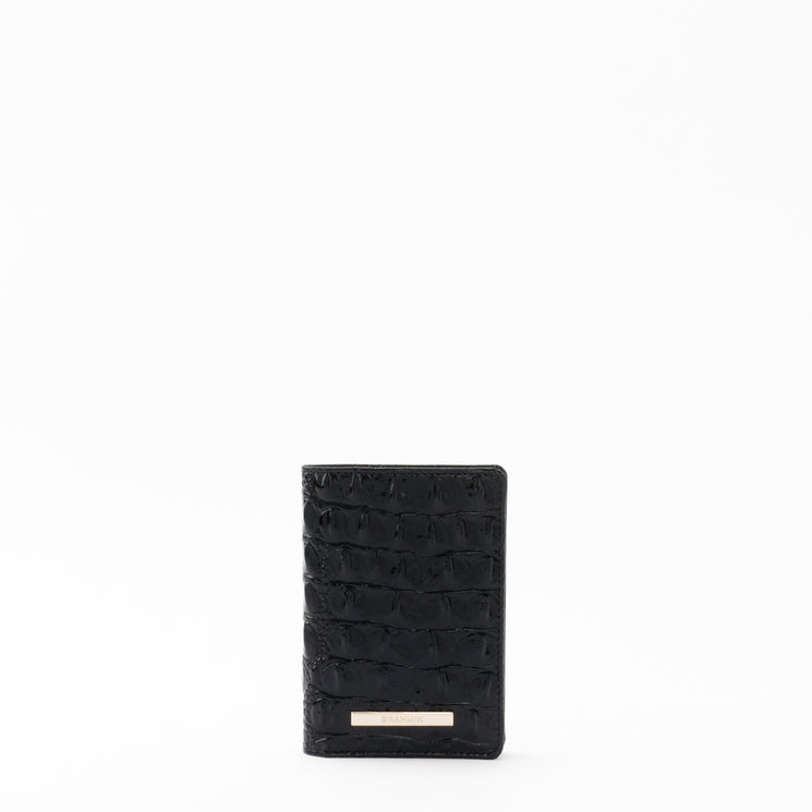Black textured Brahmin Travel Pouch Set featuring a gold rectangular nameplate, sleek silhouette, and wristlet strap, displayed against a white background. Both pouches have zip closures and subtle embossed patterning.