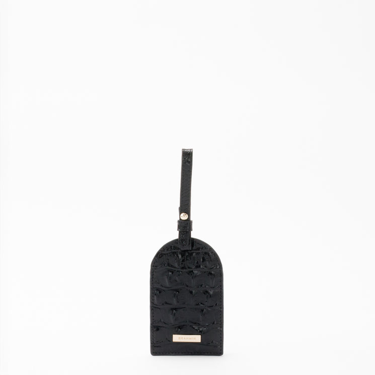 BRAHMIN Travel Pouch Set with a black textured leather luggage tag featuring a strap and buckle, and a matching passport cover. Both pieces have small gold-tone BRAHMIN logo accents on the front.