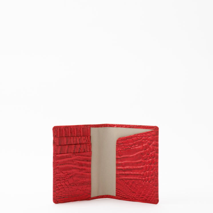 Open red BRAHMIN travel pouch set with embossed texture, wristlet strap, gold-tone hardware, card slots left, large pocket right. Interior and organization visible on white background.
