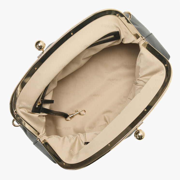 Brahmin handbag top view showing structured black silhouette, gold-tone frame and clasp, beige fabric-lined interior, zipper pocket, and interior gold hardware. No strap visible.