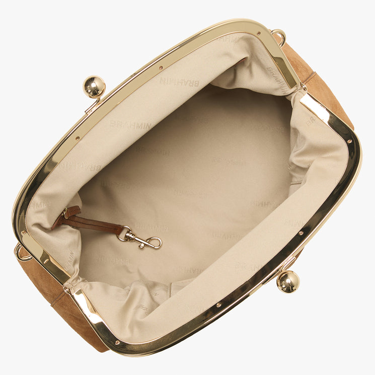 An overhead view of a structured handbag with a beige satin interior, tan leather trim, and a gold-tone metal frame with kiss-lock clasp.