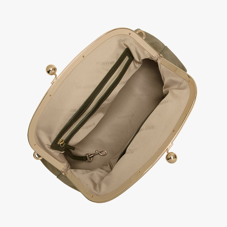 An overhead view of an open handbag showing its beige interior lining, zippered compartments, and gold-tone metal frame with decorative ball clasp details, set against a plain light gray background.