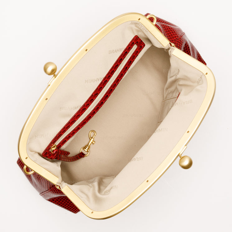 Open red textured Large Christine clutch by BRAHMIN featuring a gold-tone kiss-lock closure, beige fabric interior, zippered pocket, and a clip-on key leash.
