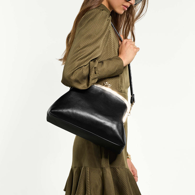 Woman holding Large Christine clutch bag on shoulder against a white background