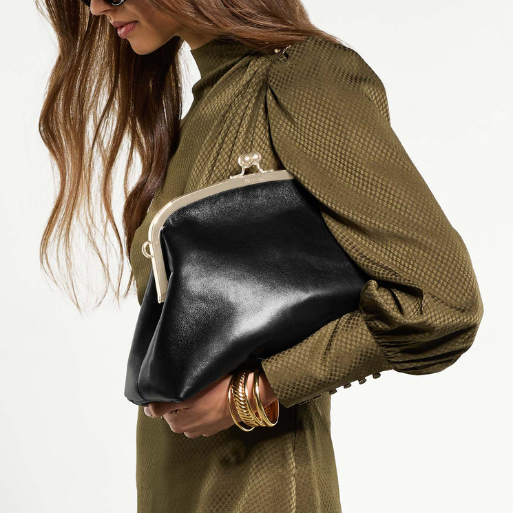 Woman holding Large Christine clutch bag with a plain background