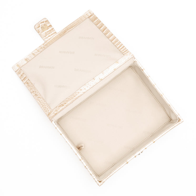 BRAHMIN Small Box clutch in cream with a croc-embossed textured exterior, gold-tone hardware, structured box silhouette, small side flap with button closure, and visible smooth BRAHMIN-print lined interior compartment.