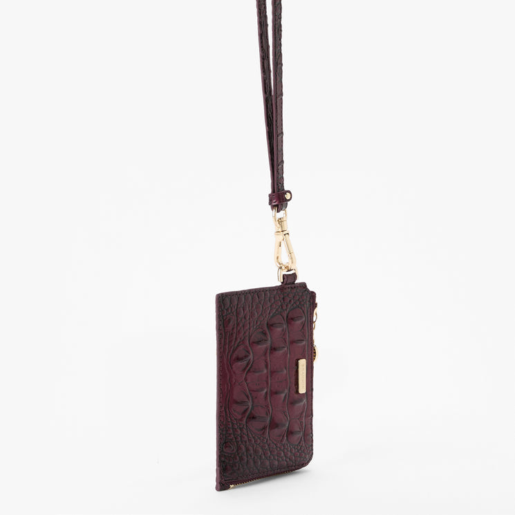 A dark burgundy crocodile-embossed leather card holder with a matching wrist strap and gold-tone hardware, shown against a plain white background.