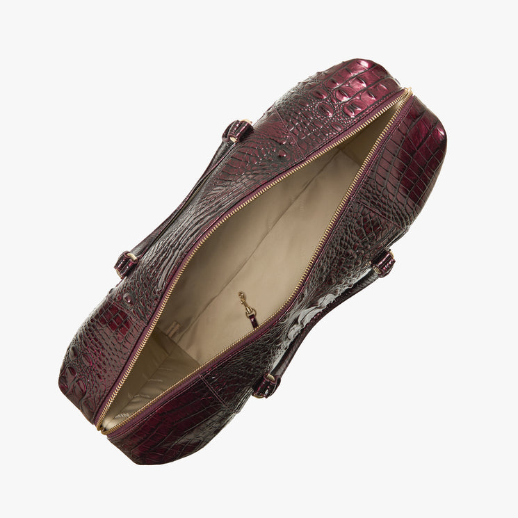 A top-down view of a dark burgundy crocodile-embossed leather handbag with a gold zipper, shown open against a light gray background.