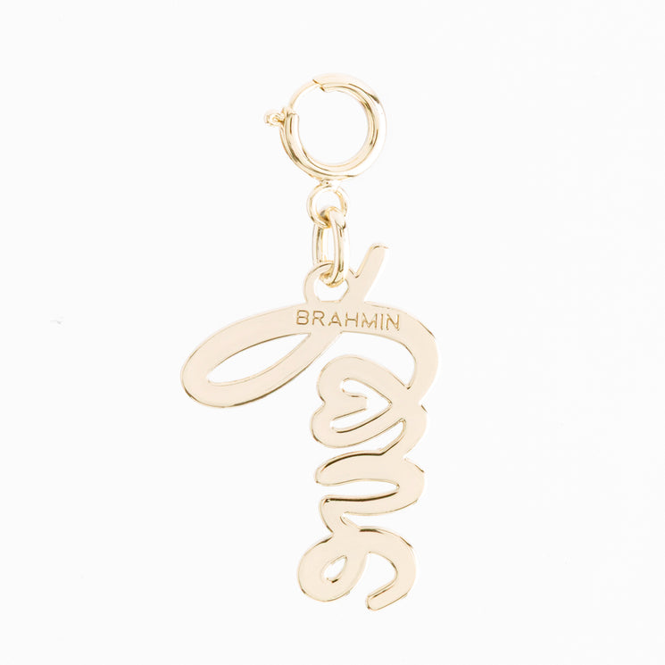 Brahmin Love Letters handbag charm in gold-tone metal, featuring the word Love in cursive script, a cutout heart detail, and a circular spring clasp.