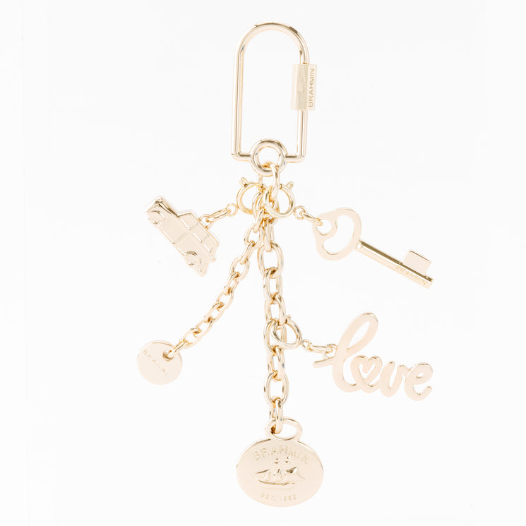 Gold-tone Brahmin Love Letters keychain with car, key, and script love charms, plus two branded round discs, all suspended from a lobster clasp.