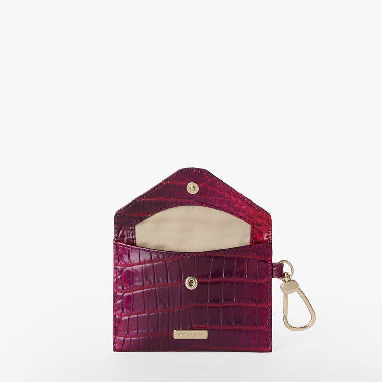 BRAHMIN Lana small envelope wallet in purple with textured, crocodile-inspired pattern, gold-tone snap closure, key clip, beige interior lining, and open design. Compact silhouette displayed in front view.