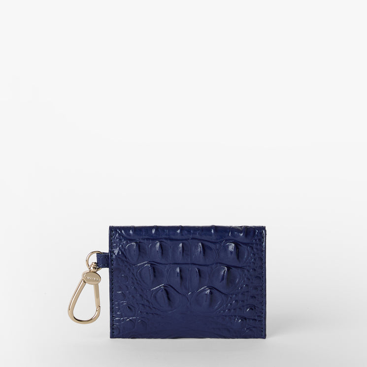 Brahmin Lana compact wallet in midnight blue embossed leather, featuring a rectangular silhouette, gold side clip hardware, and croc-inspired texture. Displayed upright on a plain white background.