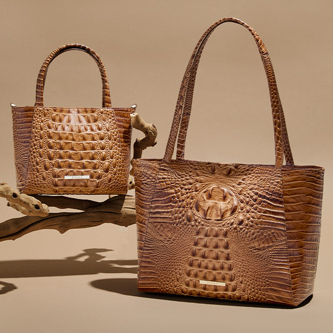 Two brown croc-embossed leather tote bags with structured shape, tall top handles, and a logo bar on the front