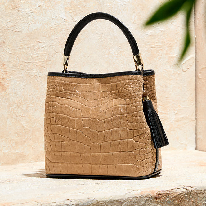 Tan croc embossed Brahmin handbag with black top handle, tassel detail, structured shape, and gold hardware.