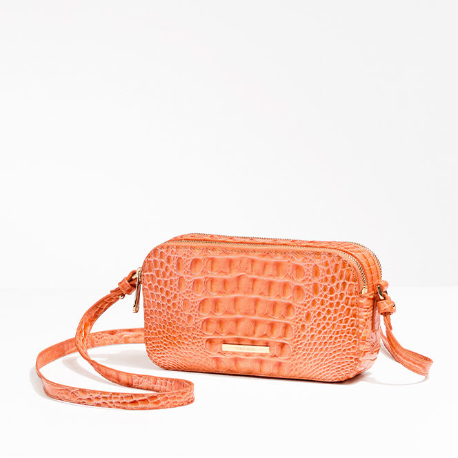 Coral-orange crocodile-embossed leather crossbody bag with a zip-top closure and slim adjustable strap, photographed on a white background