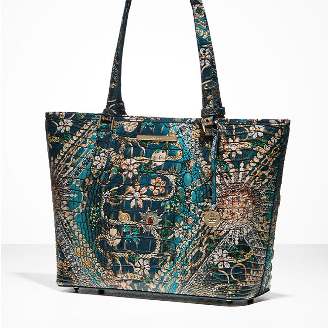 Brahmin tote bag in teal croc-embossed leather with gold and floral printed accents, displayed against a white background.